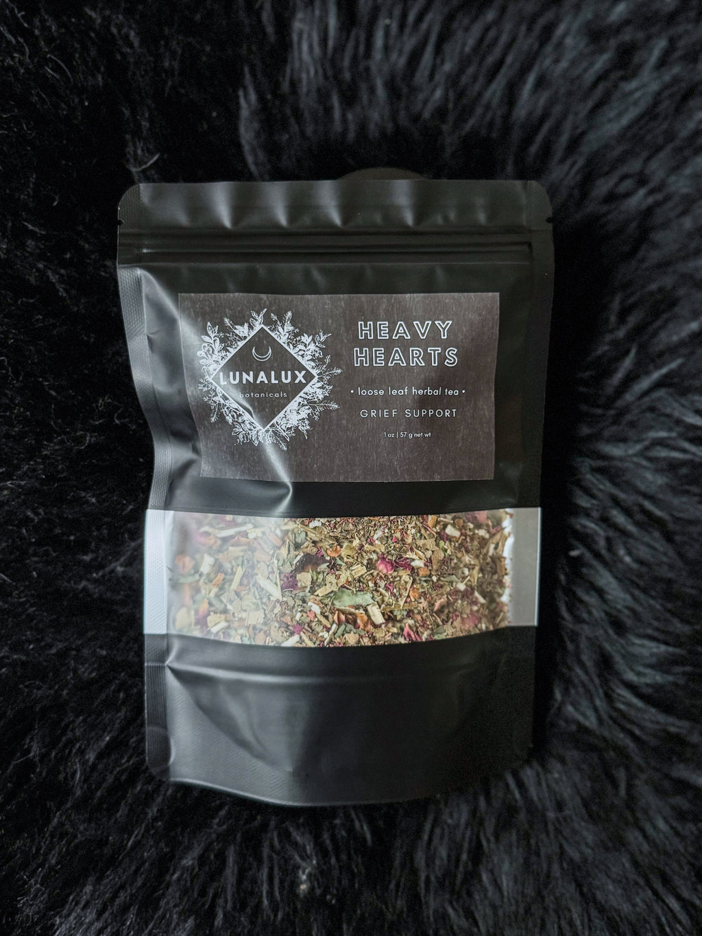 Black pouch with tea mix on a black textured background